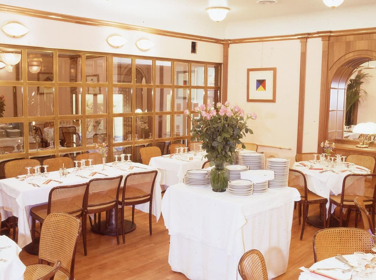 Elegant Italian restaurant dining room with white tablecloths, floral arrangements, and warm wooden furnishings.